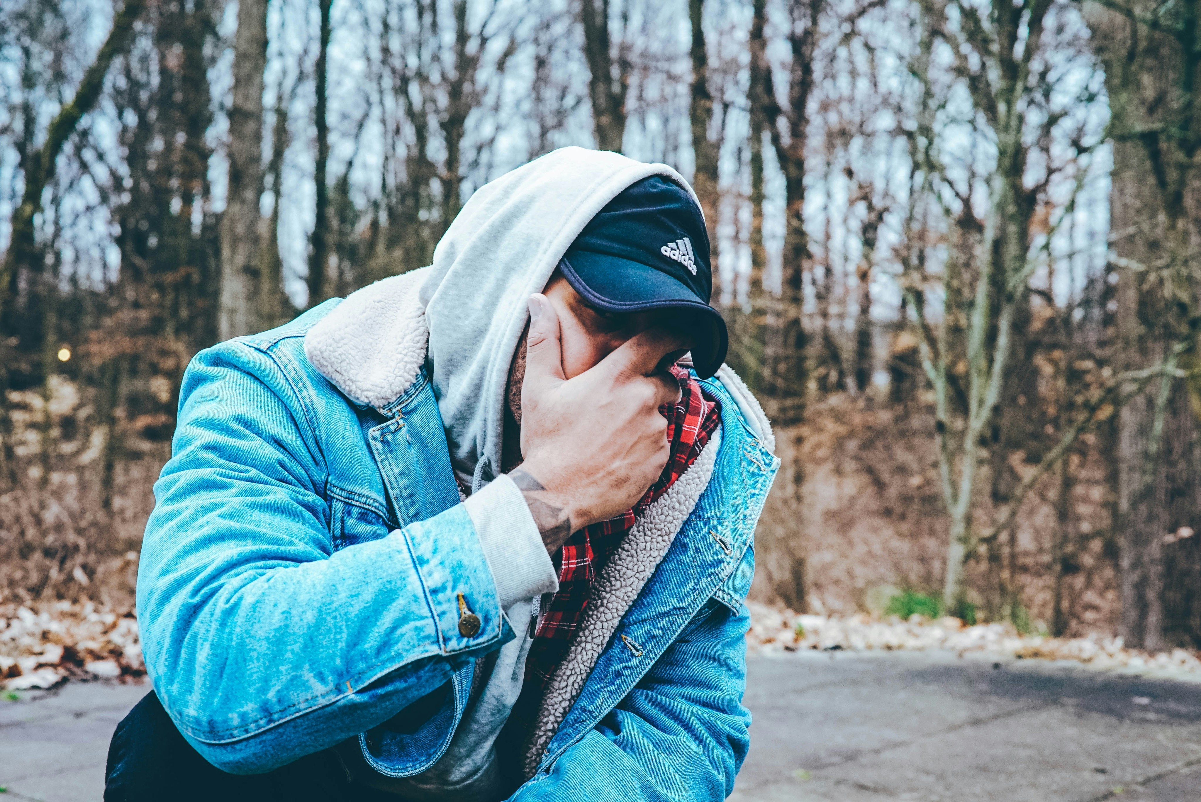 man in blue denim jacket covering his mouth with hand